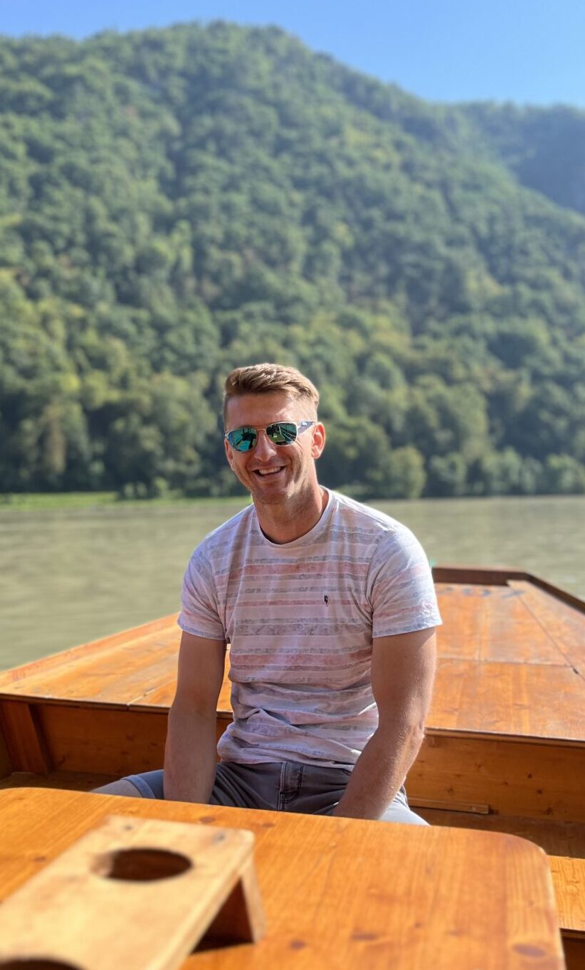 Holger, owner and boat captain at Flossmeister Regensburg, is sitting on the raft on the Danube