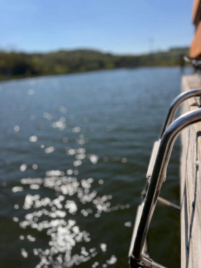 Reling eines FLOSSMEISTER-Flosses mit Blick auf das glitzernde Wasser der Donau in Bayern