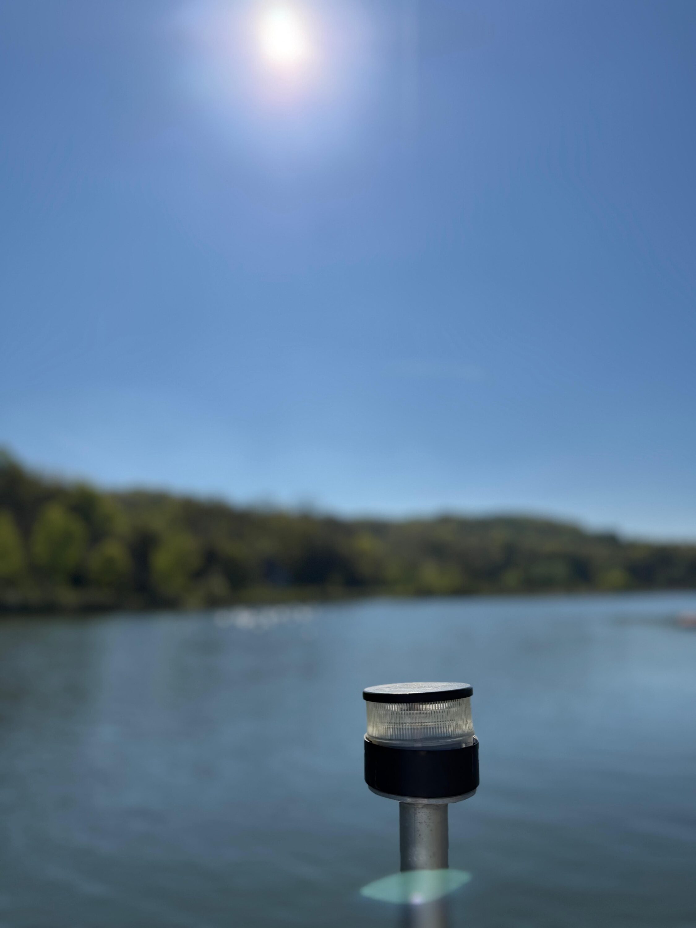 Navigationslicht am FLOSSMEISTER-Floss mit unscharfer Donaulandschaft in Bayern im Hintergrund